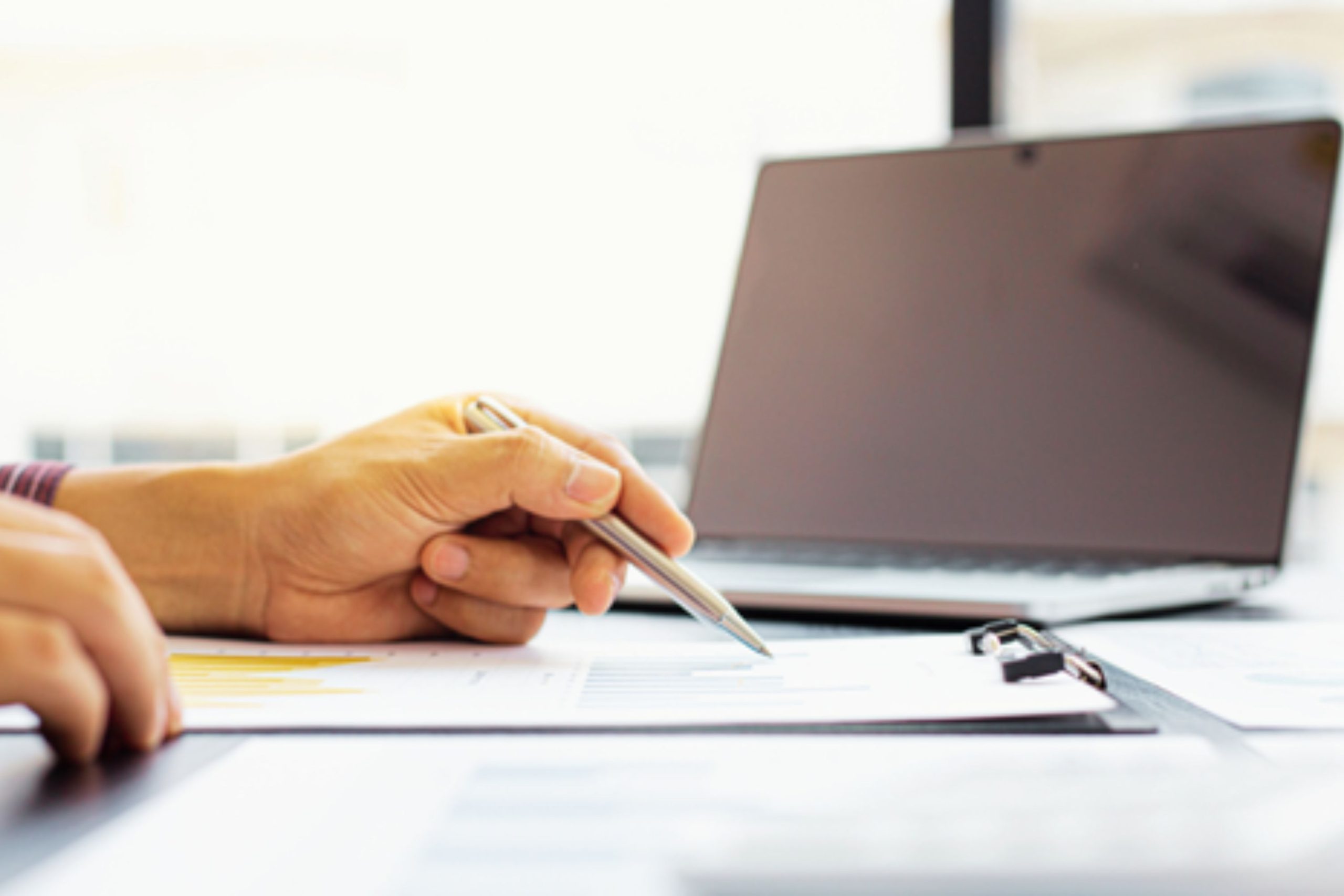 Mężczyzna robi notatki w notesie, w tle komputer