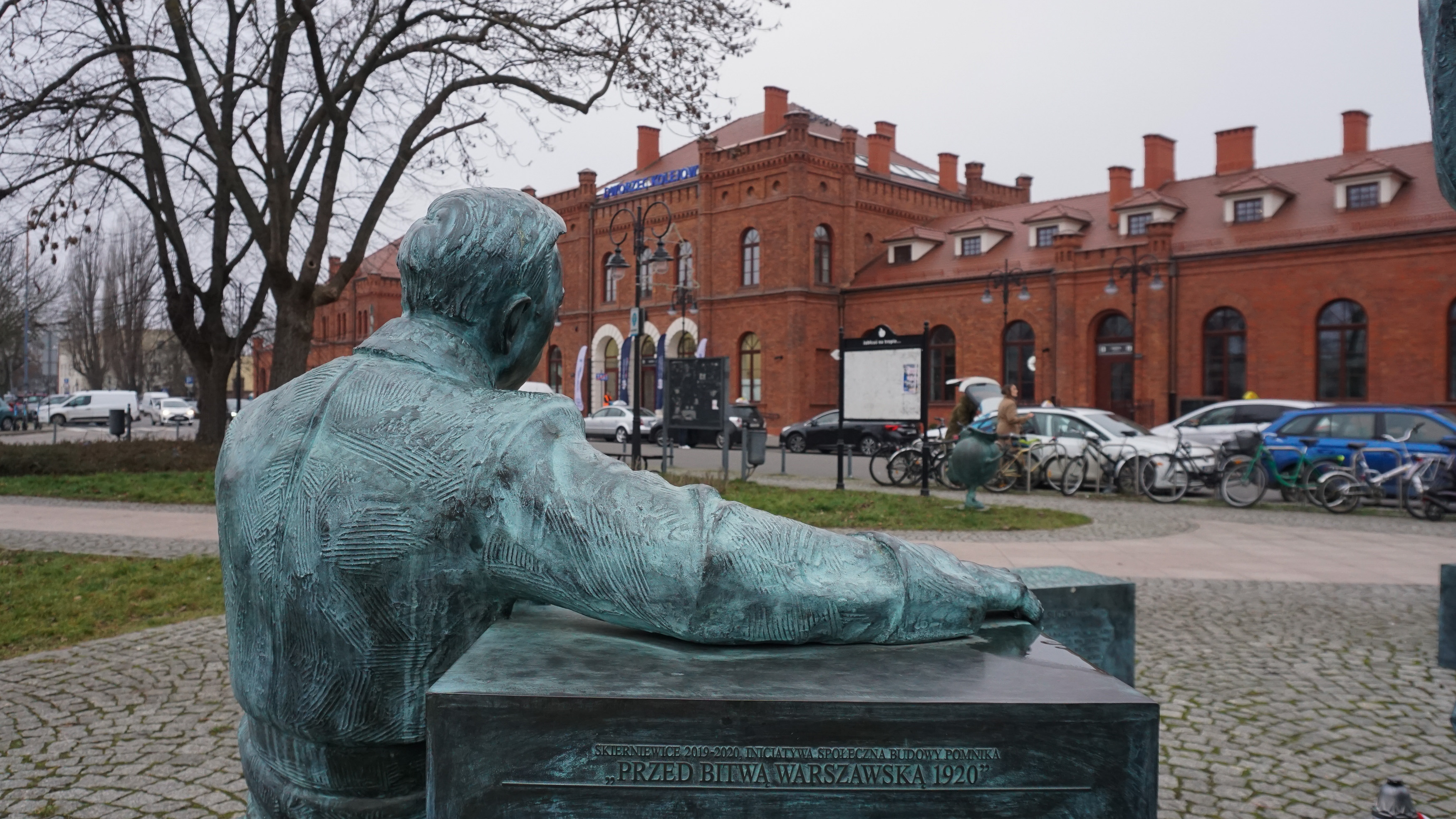 Na pierwszym planie pomnik. W tle dworzec w Skierniewicach.