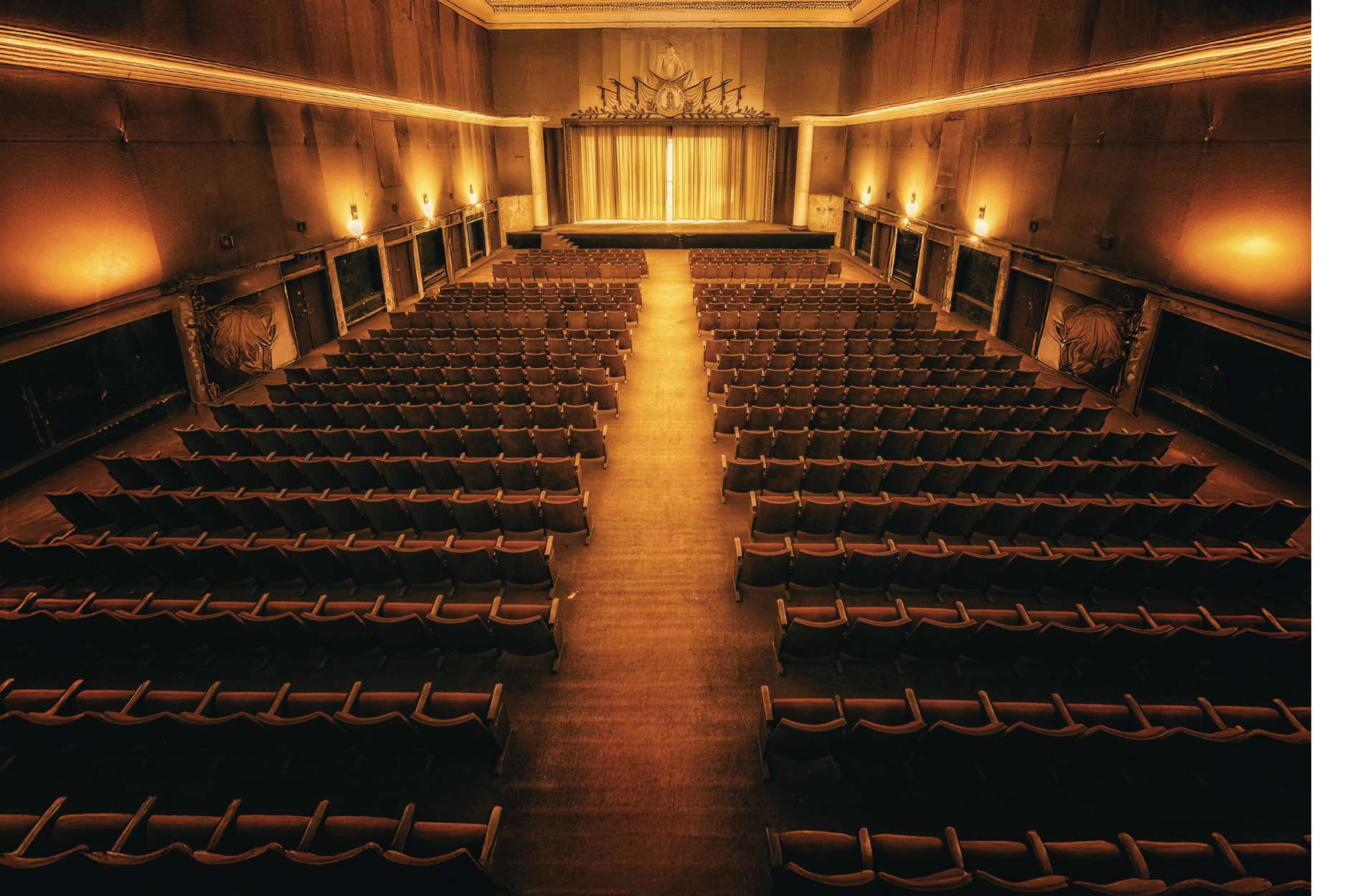 Sala teatralna delikatnie oświetlona przytłumionym światłem.